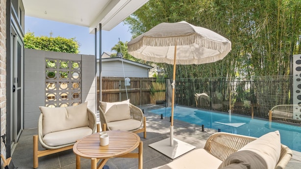 A poolside area with lounge chairs, a table, and a large umbrella. - "Serenity & Poolside Sun" - (Scarborough)