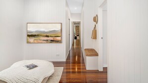 A hallway with a ceiling fan, a painting on the wall, and a bench with a cushion. - "Serenity & Poolside Sun" - (Scarborough)