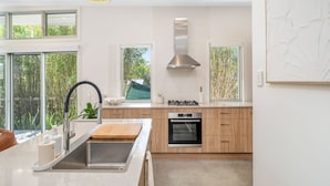 A modern kitchen with a central island, stainless steel appliances, and large windows offering views of greenery. - "Serenity & Poolside Sun" - (Scarborough)