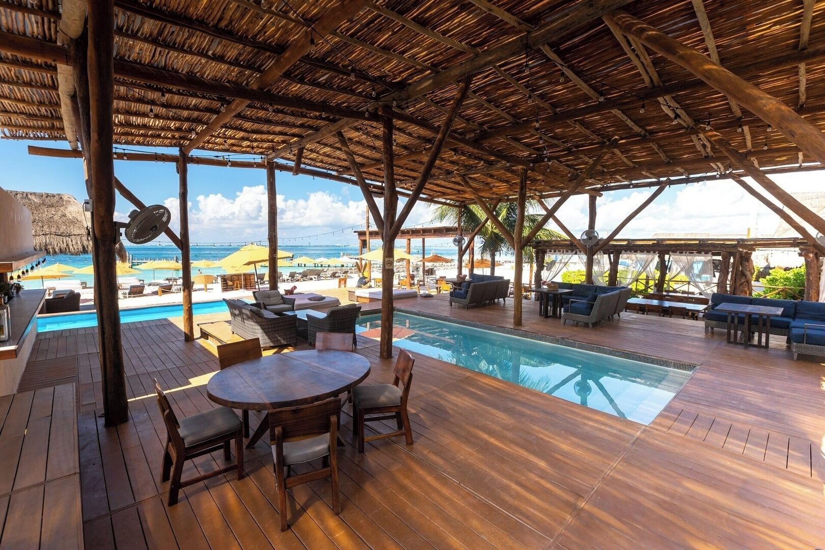 An outdoor pool area with wooden decking, lounge chairs, and umbrellas.