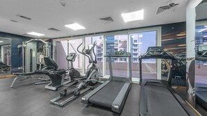 A gym with treadmills, elliptical machines, and weight equipment. - Stayshort - Business Bay for 2 With Water Views (Dubai)