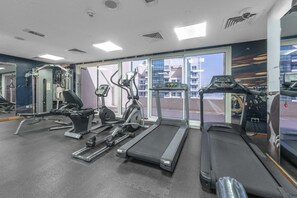 A gym with treadmills, elliptical machines, and weight equipment. - Stayshort - Business Bay for 2 With Water Views (Dubai)