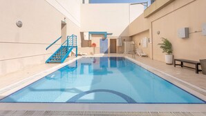 A swimming pool with a blue border, a blue staircase, and a door with a blue frame. - Stayshort - Business Bay for 2 With Water Views (Dubai)