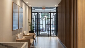 A reception area with a modern design, featuring a reception desk, seating area, and a view of the parking lot through a glass door.