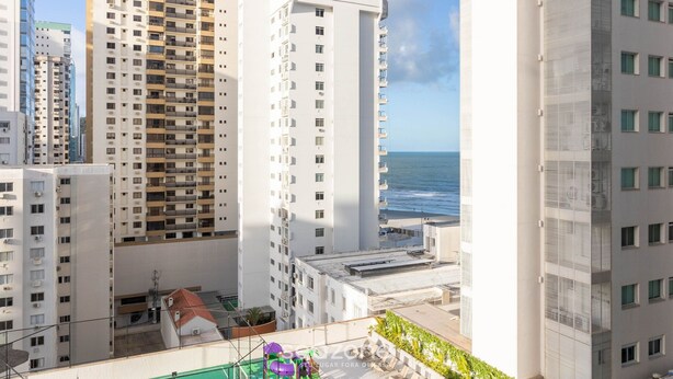 A high-rise building with multiple balconies overlooking a coastal area.