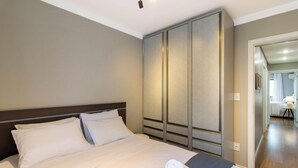 A hotel room with a large bed, a wardrobe, and a view of the bathroom.