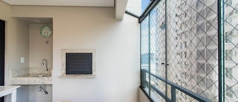 Un baño con lavamanos, espejo y ventana con vista a un edificio.