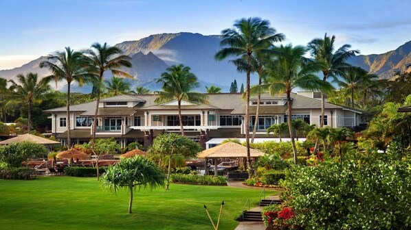 Ein Resort mit einem großen Gebäude, Palmen und einem Berg im Hintergrund.