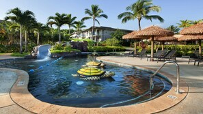 Ein Pool mit Wasserrutschen, Liegestühlen und Palmen.