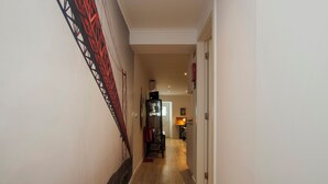 Ein Flur mit Holzboden, einer Treppe mit roten Geländern und einer Tür zu einem Zimmer.