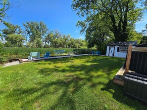 A backyard with a grassy lawn, a small shed, and outdoor seating.