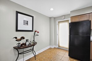 A kitchen with a black refrigerator, a framed picture on the wall, and a small table with decorative items.