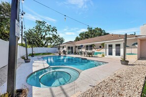 A backyard with a swimming pool, outdoor furniture, and a white fence.