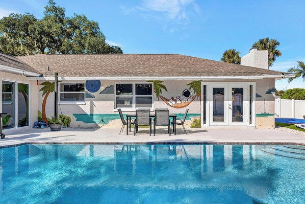 A poolside area with a hammock, patio furniture, and a view of the pool.