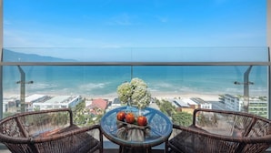 A balcony with wicker chairs and a glass table with fruit and a vase. - Canvas Hotel (Da Nang)