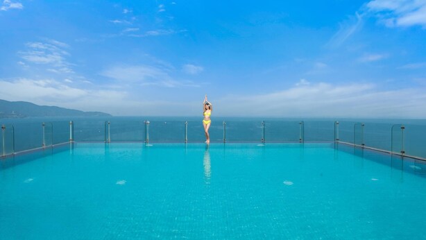 A pool with a clear view of the ocean and distant mountains. - Canvas Hotel (Da Nang)