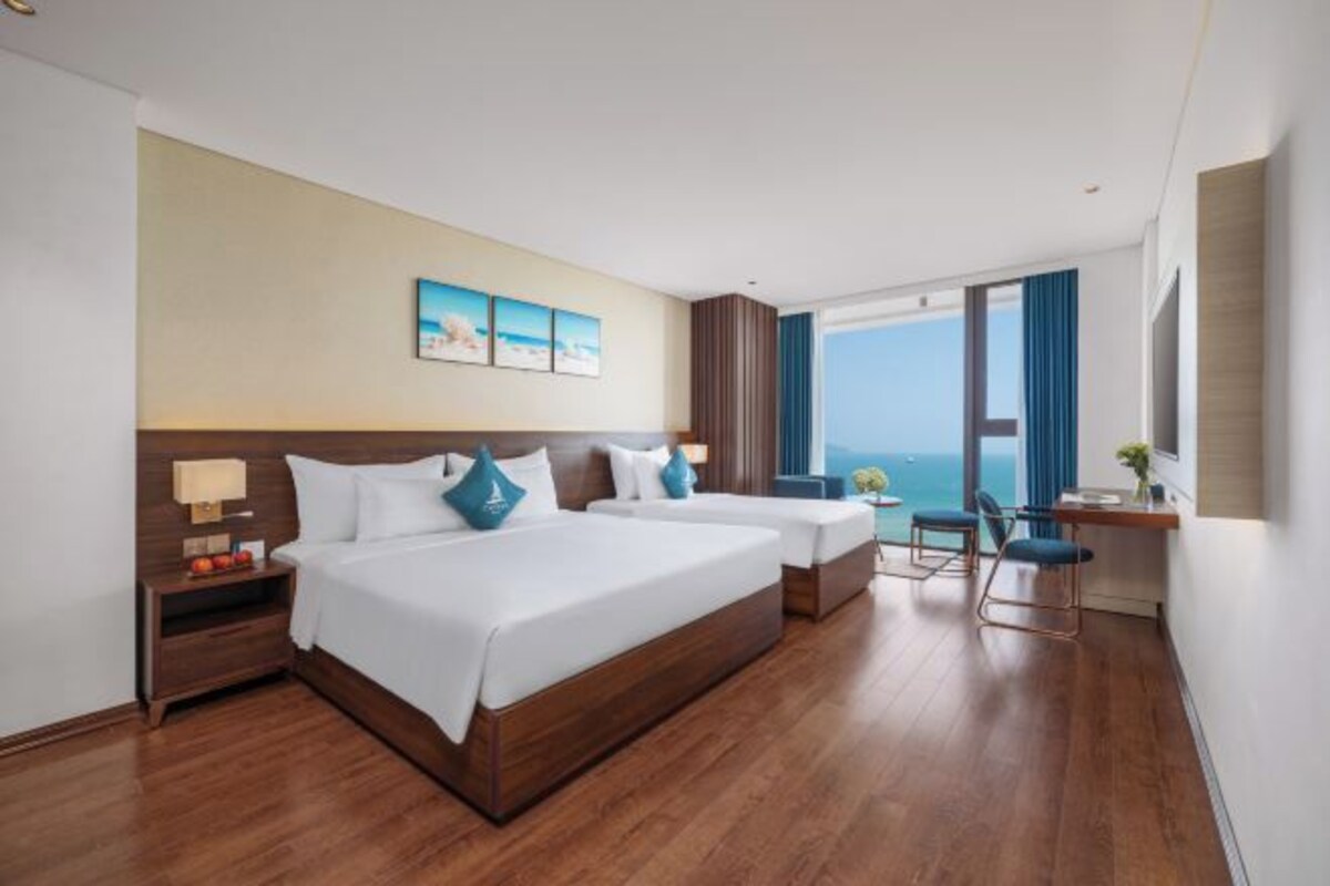 Ein Hotelzimmer mit zwei Betten, einem Schreibtisch, einem Sessel und einem großen Fenster mit Blick.