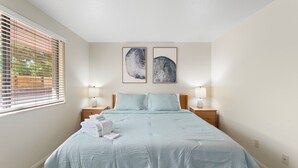 A bedroom with a bed, two bedside tables with lamps, a window with blinds, and two wall-mounted artworks. - Desert Dream Escape – Spacious 2BR Getaway (Sedona)