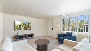 A modern living room with a large flat-screen TV, a round coffee table, and a sofa. - Desert Dream Escape – Spacious 2BR Getaway (Sedona)