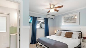 A bedroom with a bed, a ceiling fan, a nightstand, and a window with curtains. - Waterfront Bliss with Pool, Dock & Patio Retreat (Treasure Island)
