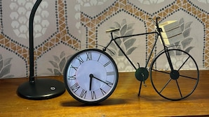 Une horloge à chiffres romains et un vélo, tous deux posés sur une surface en bois.