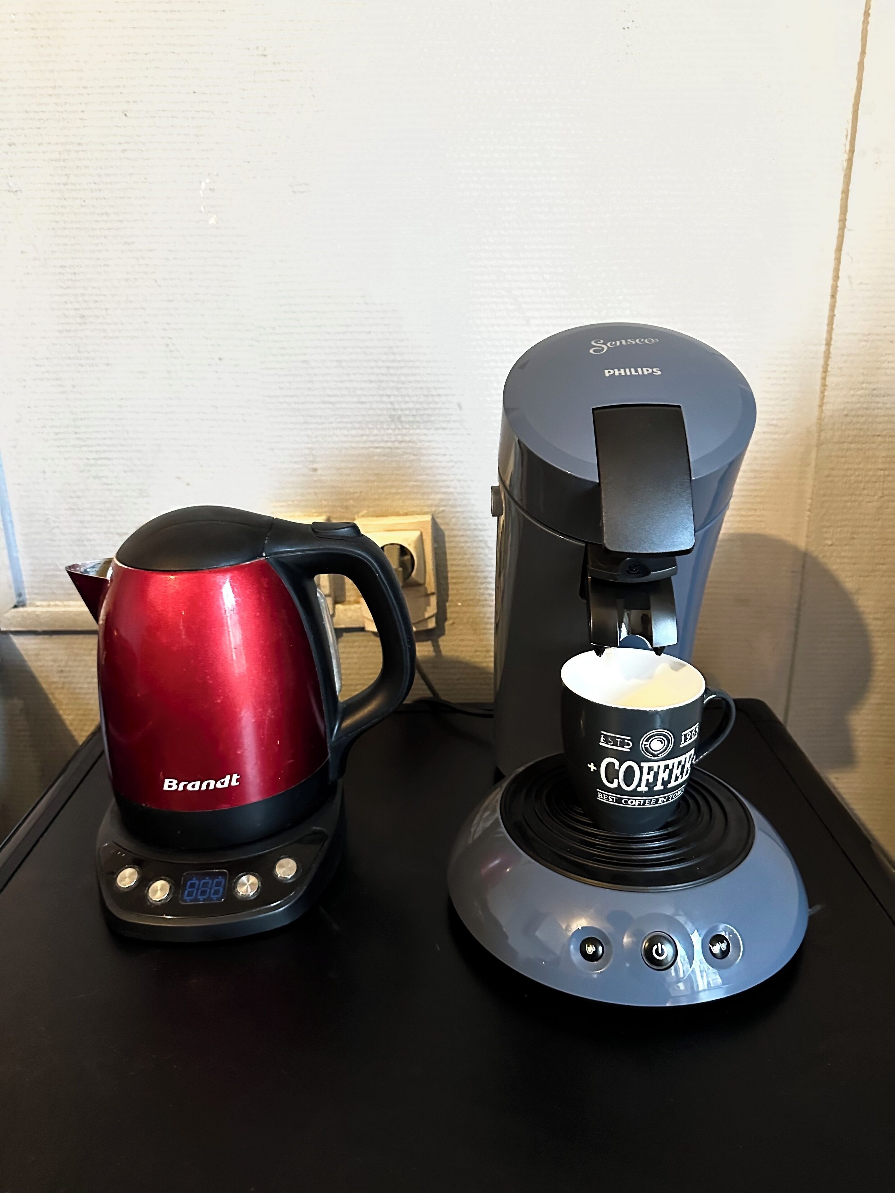 A coffee maker and a kettle on a black countertop.