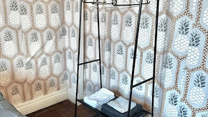 Une pièce avec un lit en métal noir, un mur orné de motifs et un plancher en bois.