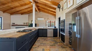 A modern kitchen with a stone floor, wooden ceiling beams, and a built-in wine rack. - Country Escape - 3BR Home with Panoramic Views (Mansfield)