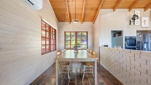 A wooden interior with a dining table, chairs, and a kitchen area with appliances. - Country Escape - 3BR Home with Panoramic Views (Mansfield)