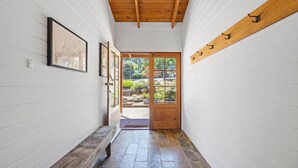 A hallway with white walls, a wooden bench, and a door leading outside. - Country Escape - 3BR Home with Panoramic Views (Mansfield)