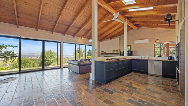 A spacious kitchen with a large island, a dining area with a sofa, and a view of the outdoors. - Country Escape - 3BR Home with Panoramic Views (Mansfield)