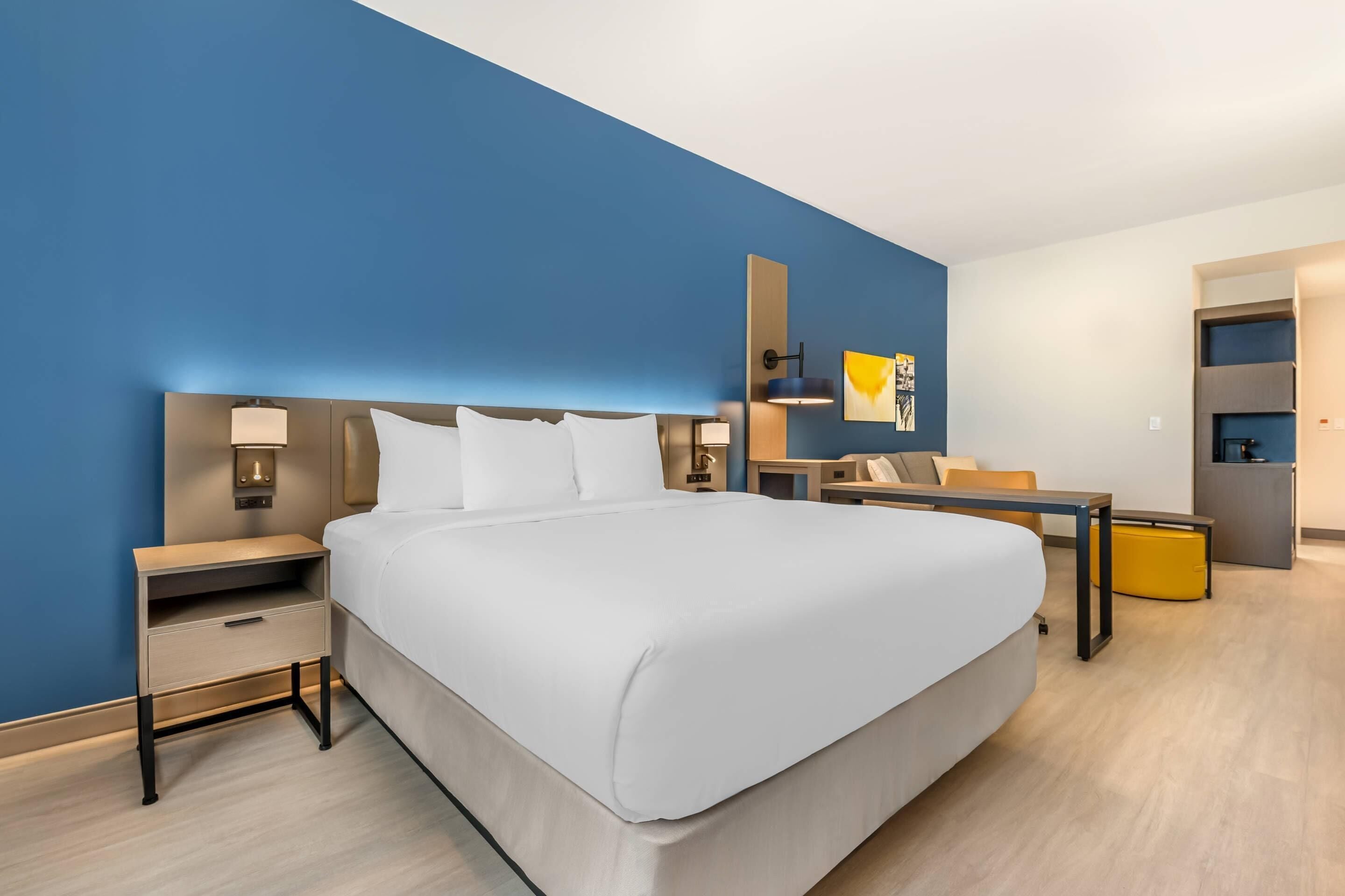 A modern hotel room with a large bed, bedside tables, a desk, and a chair.