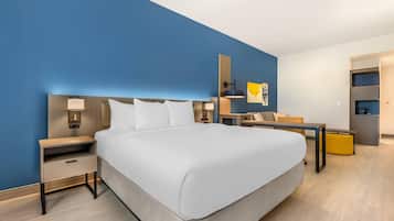 A modern hotel room with a large bed, bedside tables, a desk, and a chair.