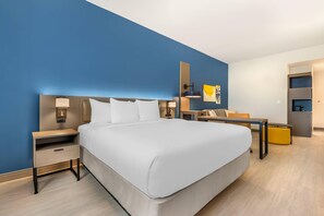 Una habitación de hotel moderna con una cama grande, mesitas de noche, un escritorio y una silla.