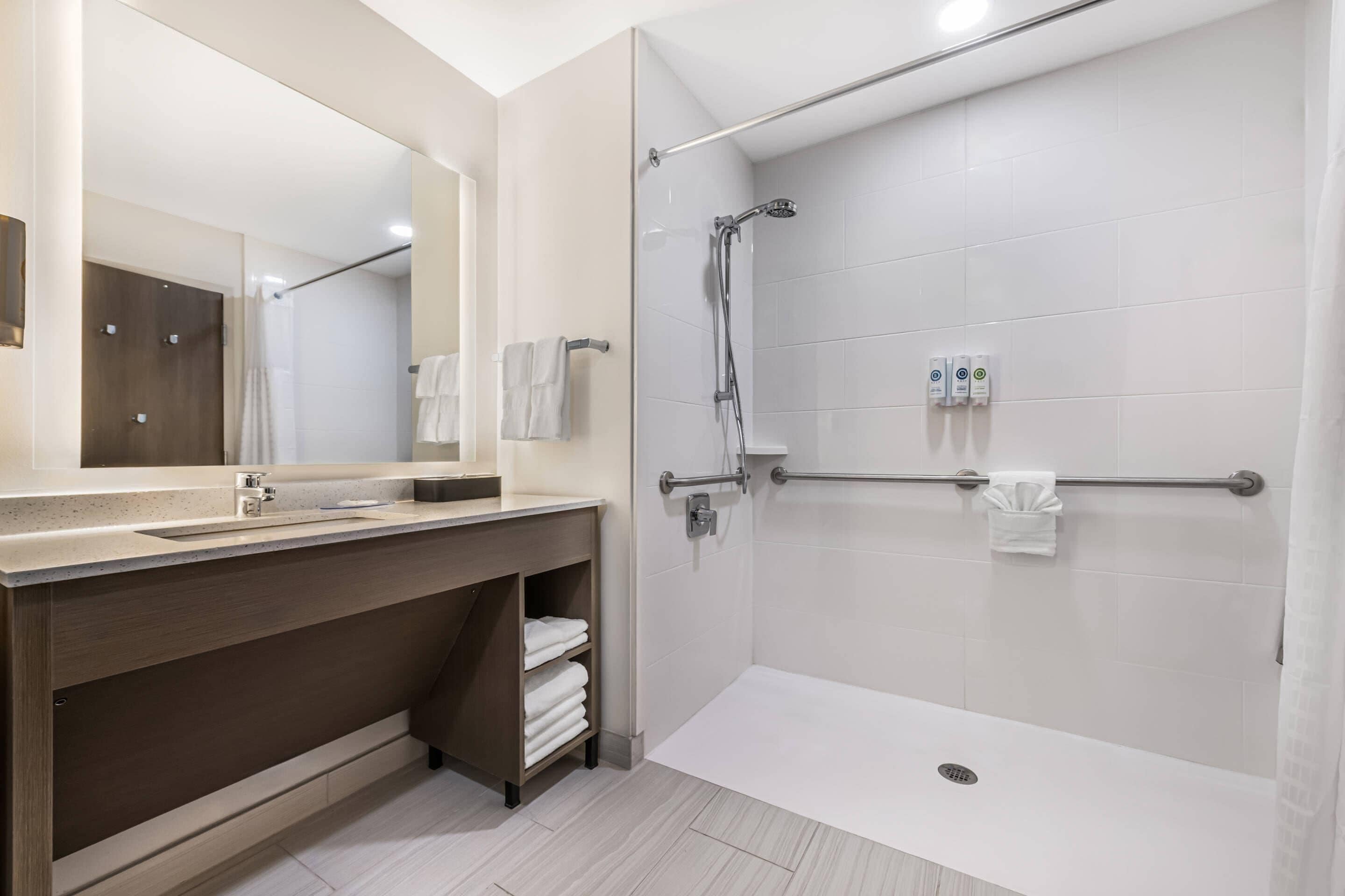Un bagno moderno con doccia, lavandino e specchio.