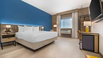 Ein modernes Hotelzimmer mit einem großen Bett, Nachttischen, einem Schreibtisch mit Stuhl und einem an der Wand befestigten Fernseher.
