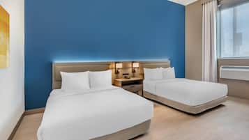 A hotel room with two beds, a nightstand with lamps, and a window with curtains.