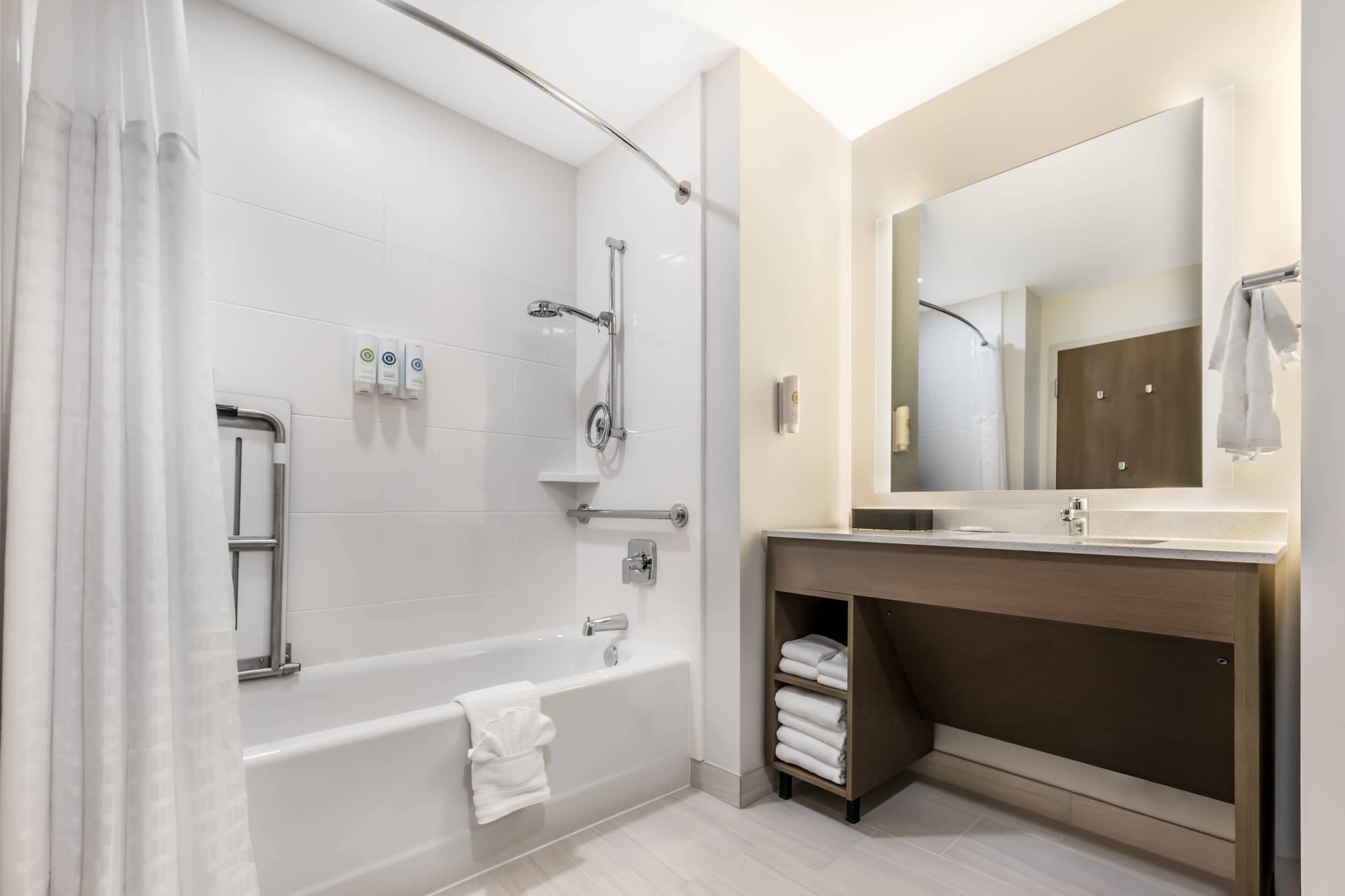 A modern bathroom with a bathtub, shower, and vanity.