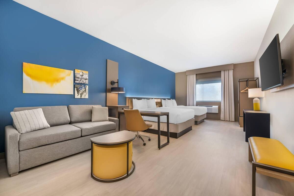 Ett hotellrum med en säng, en soffa, ett skrivbord och en tv.