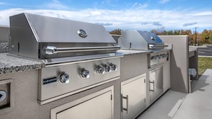 Cocina exterior de acero inoxidable con una parrilla a gas, un quemador lateral y un lavamanos incorporado.