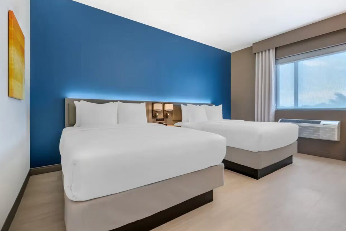 Ein Hotelzimmer mit zwei Betten, einem großen Fenster und einem modernen Design.
