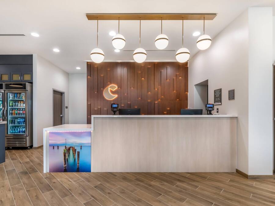 A reception area with a wooden reception desk, a digital display, and a vending machine.