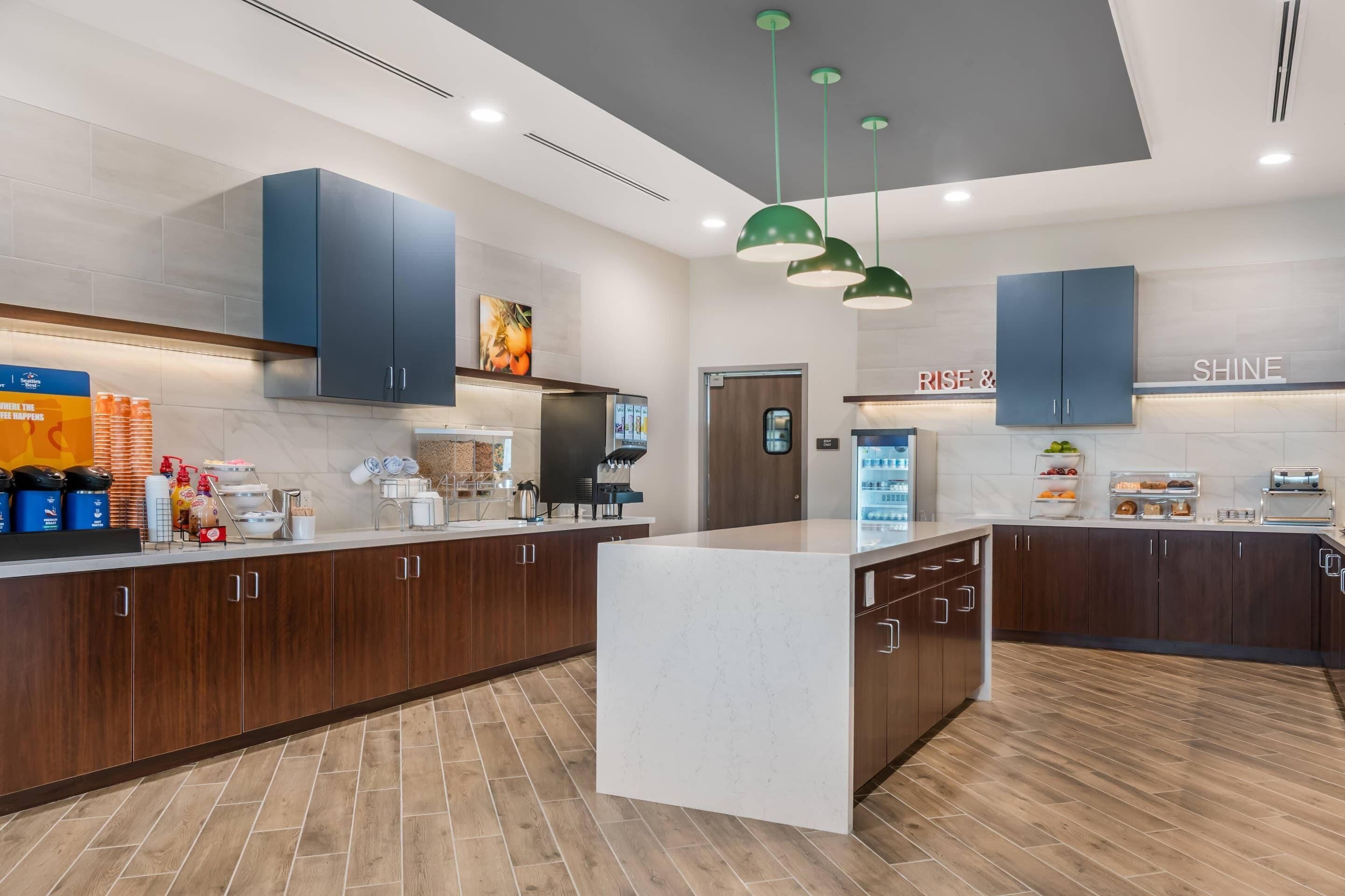 Una cocina moderna con armarios de madera oscura, encimera de mármol y lámparas colgantes verdes.