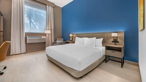 Una habitación de hotel moderna con una cama grande, mesitas de noche con lámparas, un escritorio y una silla.