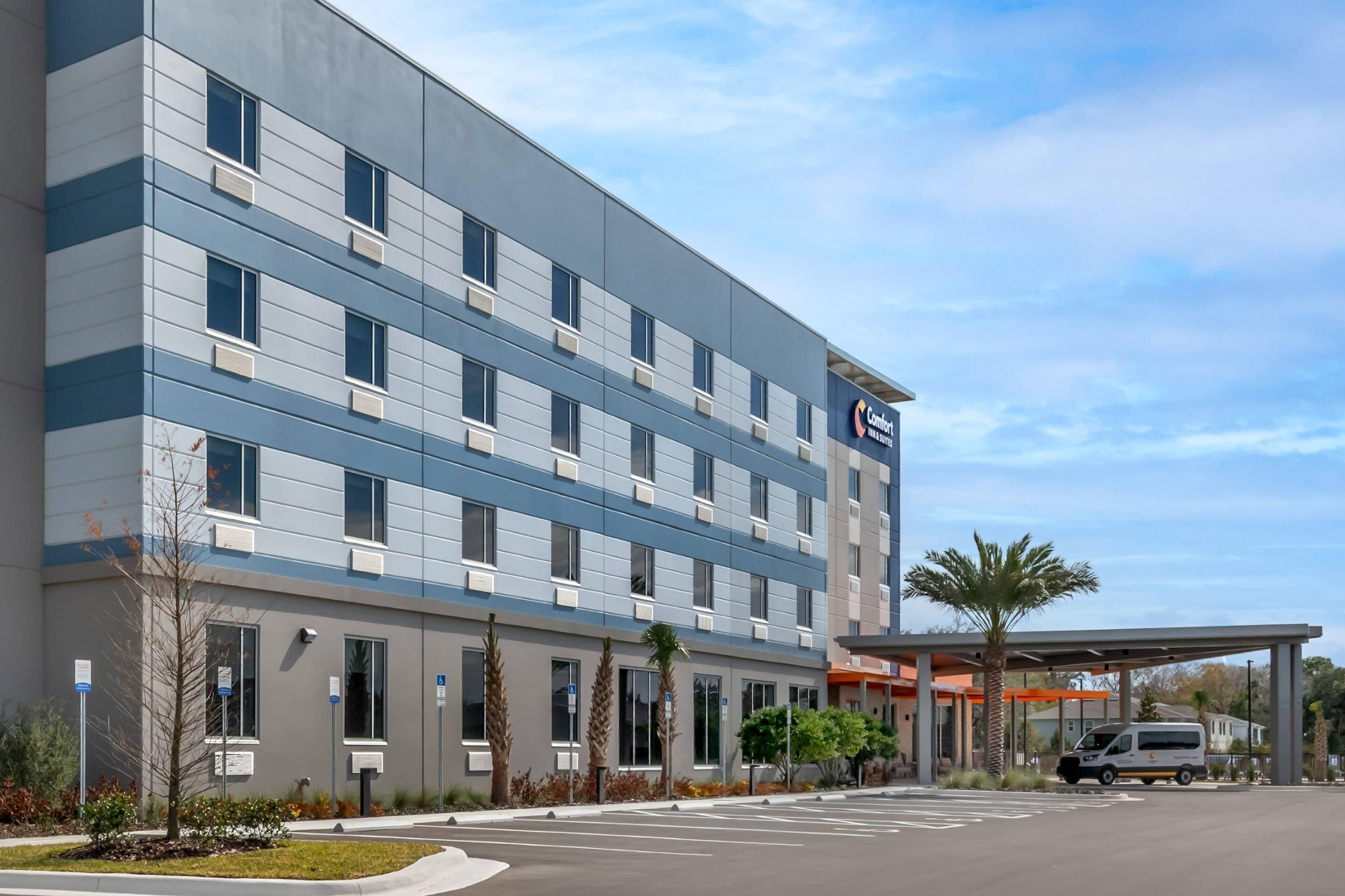 A modern hotel building with a flat facade, multiple windows, and a parking lot.