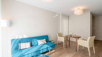 Una sala de estar moderna con un sofá azul, dos sillones, una mesita y una mesa redonda de centro.