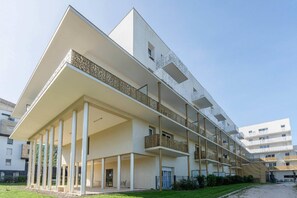 A modern multi-story building with a flat roof, balconies, and a covered outdoor area with columns. - Quality Aparthotel Grenoble Sud (Echirolles)