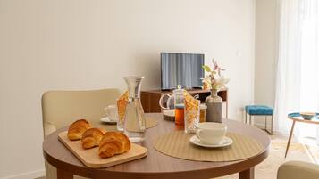 Un comedor con una mesa redonda dispuesta para el desayuno, incluyendo croissants y una jarras.