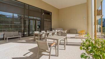Un patio al aire libre con varias mesas y sillas, un banco y una planta en maceta.