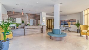 Un hall d’hôtel moderne comprenant un comptoir d’accueil, des espaces de détente et une grande colonne.